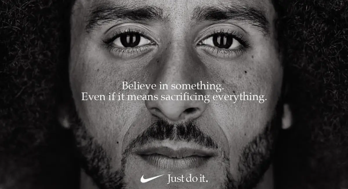 A black-and-white close-up of a man with intense eyes and curly hair, overlaid with the text 'Believe in something. Even if…