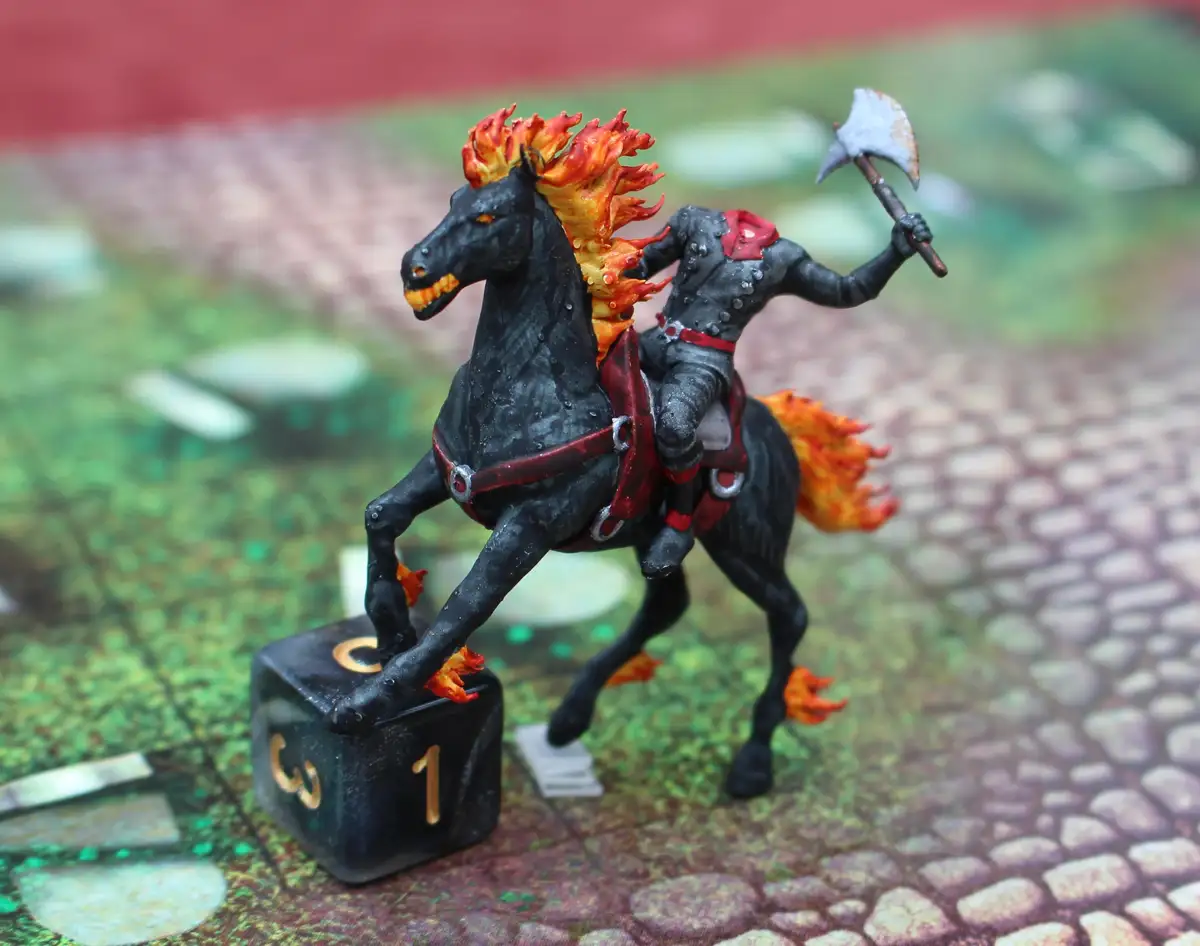 A painted miniature of a flaming black horse with a rider wielding an axe stands atop a black six-sided die showing the…