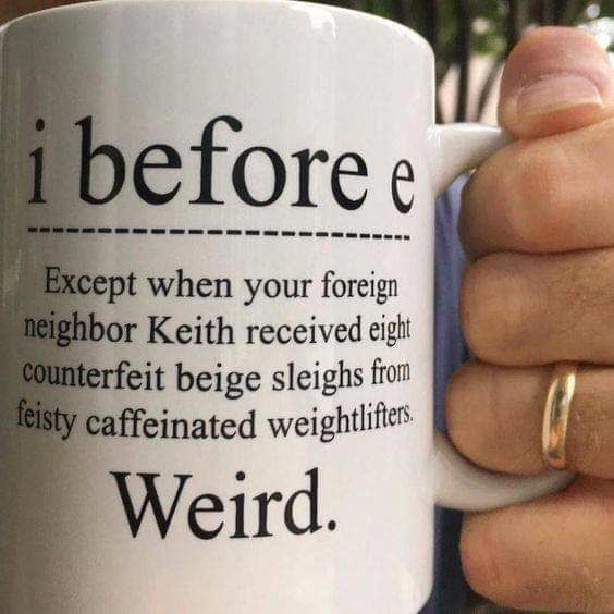 A white ceramic mug held by a hand with a gold ring, displaying text that humorously redefines the spelling rule 'i before…
