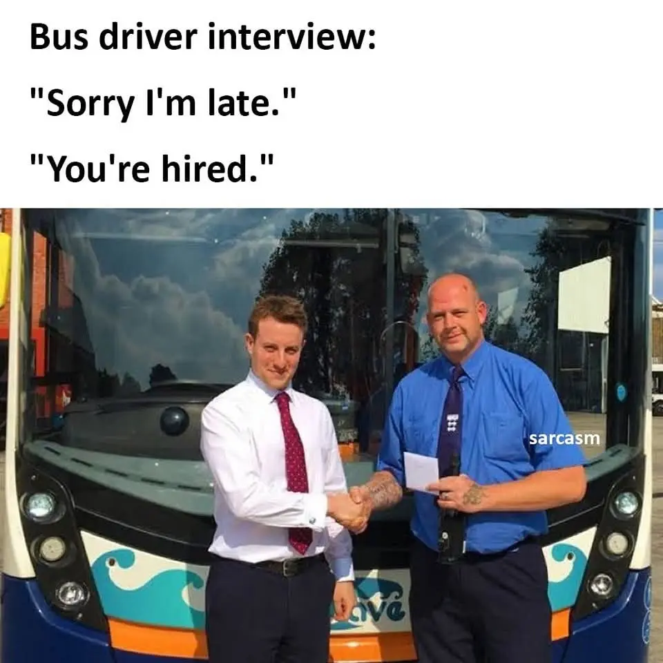 Two men are shaking hands in front of a blue and white bus with wave patterns. The man on the left wears a white shirt and…