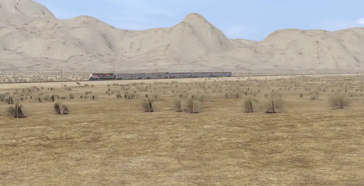 A long passenger train travels across a vast, arid desert landscape with sparse vegetation and distant, barren mountains…