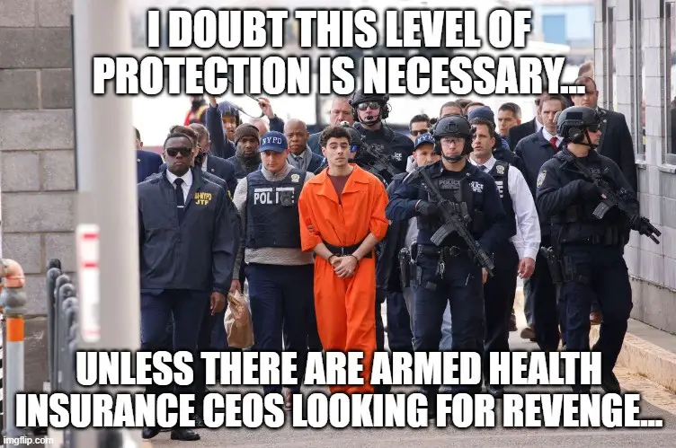 A man in an orange prison jumpsuit is escorted by numerous heavily armed police officers in tactical gear. The overlaid text…