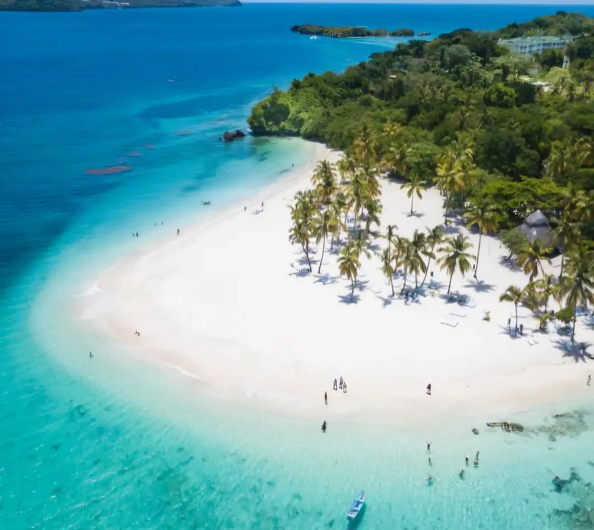 An aerial view of a stunning tropical beach with white sand, turquoise water, and palm trees, with small figures of people…