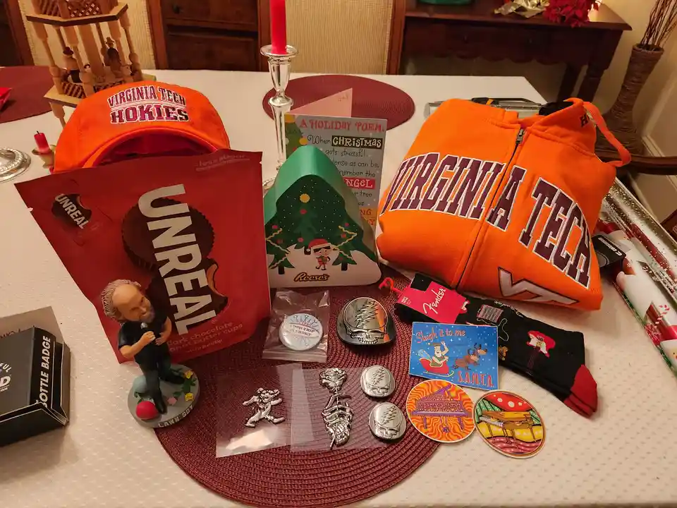 A table displays a collection of Virginia Tech-themed gifts including an orange hoodie and cap, alongside Christmas items…