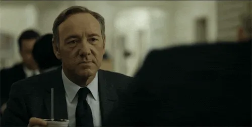 six panels show actor Kevin Spacey in a dark suit holding a drink with a straw, looking progressively more serious and…