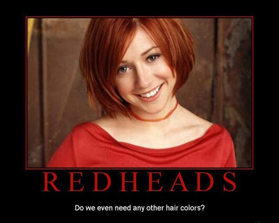 A smiling woman with short red hair and a red top is framed in a black border. Below her image, bold red text reads…
