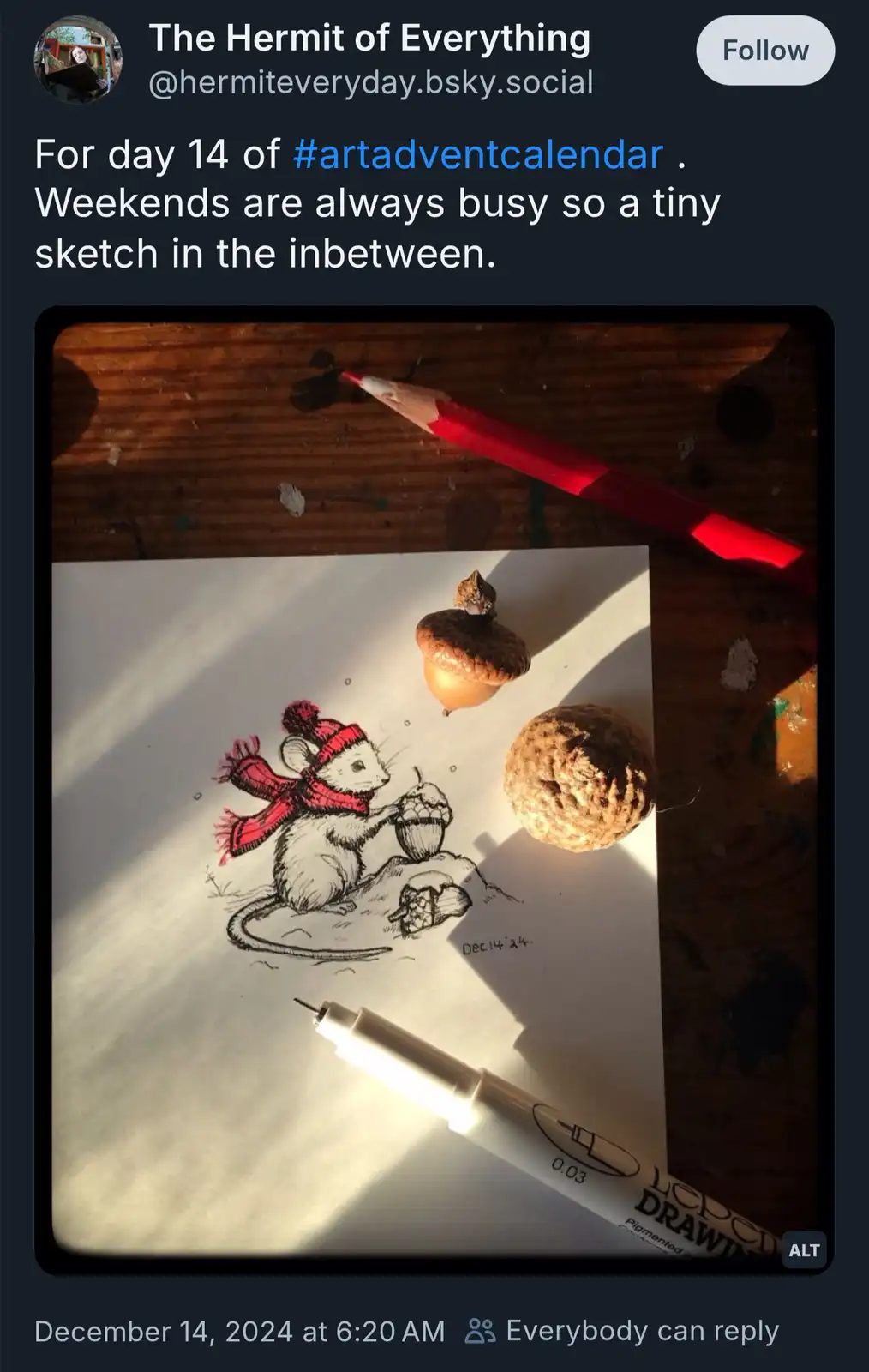 A close-up photo shows a small, detailed sketch of a mouse wearing a red hat and scarf, holding an acorn, on a piece of…