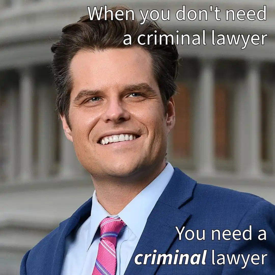A man in a blue suit and pink tie smiles confidently in front of a building with columns. White text overlaid at the top…