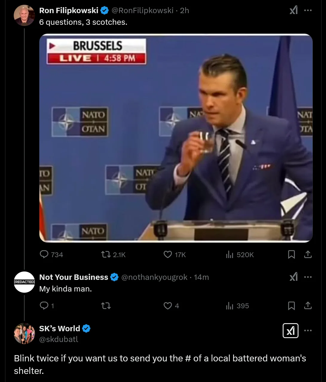 A man in a blue suit stands at a podium with NATO logos behind him, holding up a small glass of scotch. The overlaid text…
