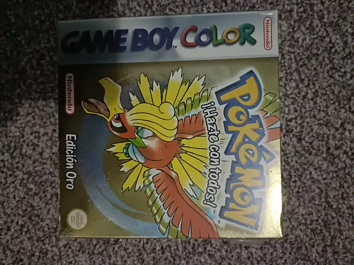A sealed Game Boy Color box for the Pokémon game, featuring the character Ho-Oh on a gold background. The box is labeled…