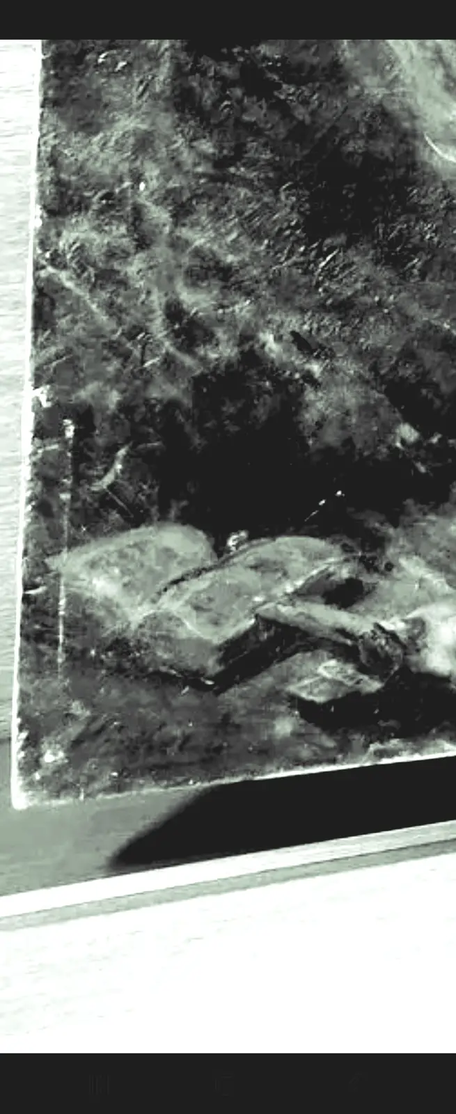 A grainy, black-and-white photo shows a blurry, low-resolution image of what appears to be a book or magazine lying on a…