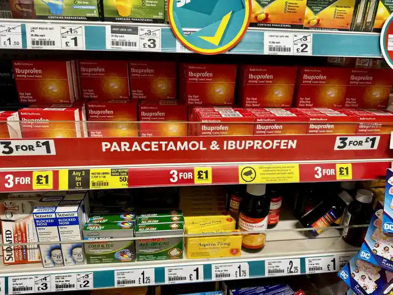 A supermarket shelf displays boxes of Bell's Healthcare Ibuprofen and other pain relief products under a red banner that…