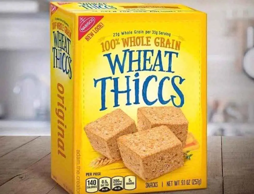 A yellow box of Nabisco Wheat Thiccs cereal snacks sits on a wooden surface, featuring three thick, square-shaped…