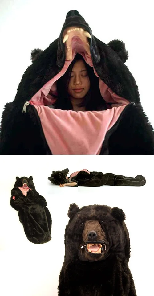 A person is shown inside a large black bear-shaped sleeping bag with the hood open, revealing their face. The image also…