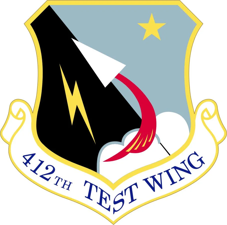 The image displays the official crest of the 412th Test Wing, featuring a shield with a black background, a white arrowhead…