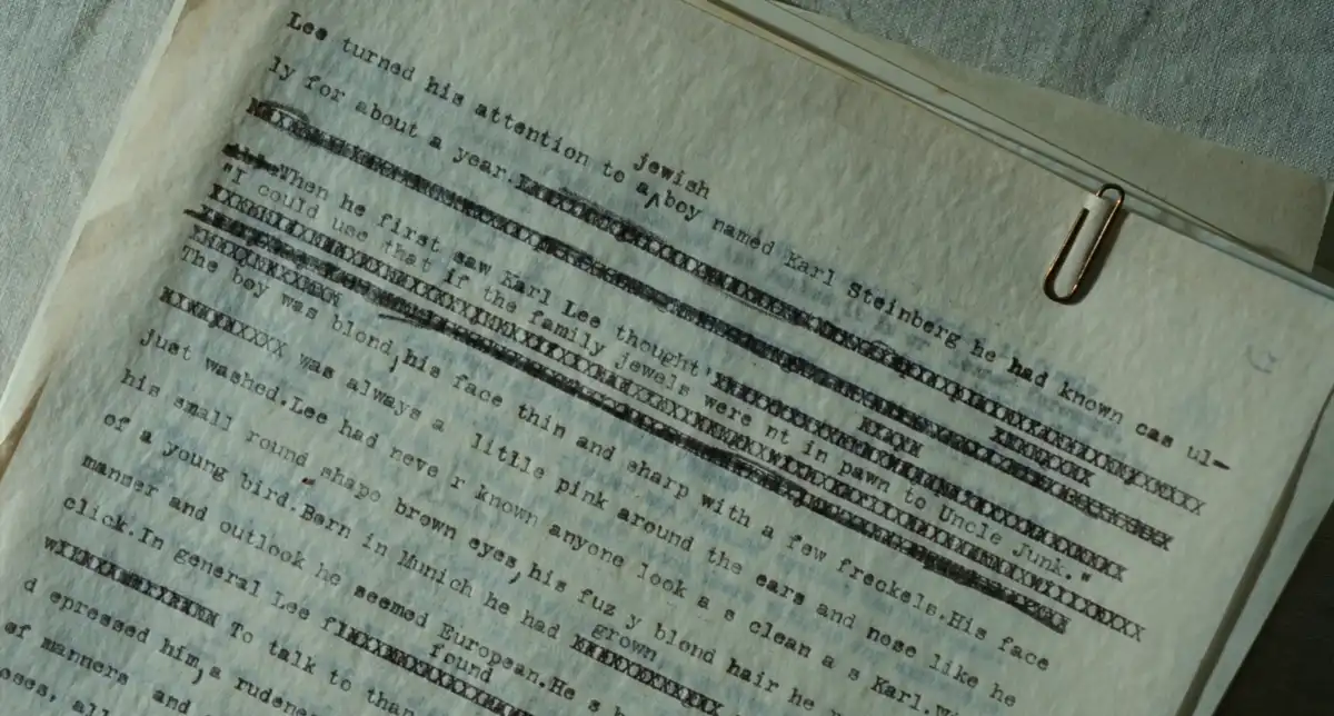 A close-up of a typewritten document with several lines of text heavily crossed out with black marker, revealing a narrative…