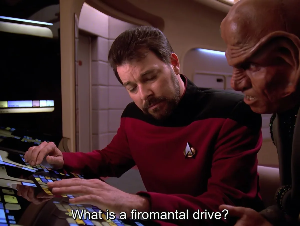 Two men in Star Trek uniforms are at a control panel; one is typing while the other looks on. The text overlay asks 'What is…