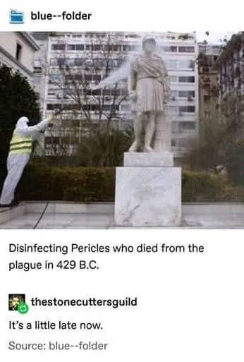 A person in a white hazmat suit with a yellow reflective vest sprays a large marble statue of a man in ancient Greek attire…
