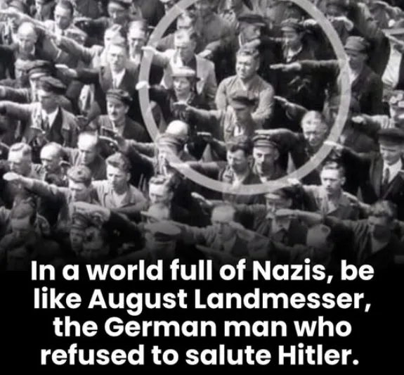 A black-and-white historical photograph shows a large crowd of men in uniform performing the Nazi salute. One man in the…