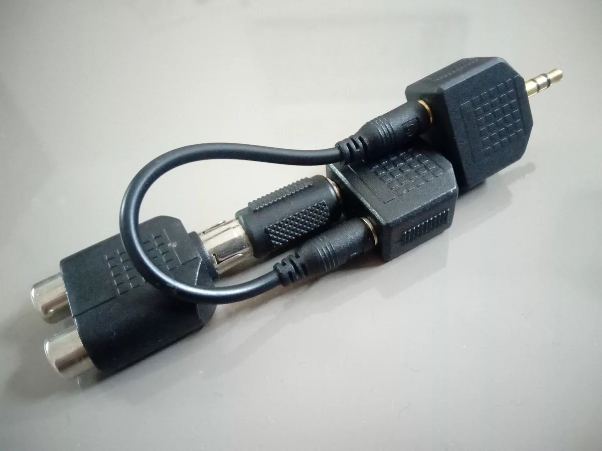 A black cable adapter with multiple connectors, including a 3.5mm jack, RCA plugs, and a BNC connector, arranged in a…