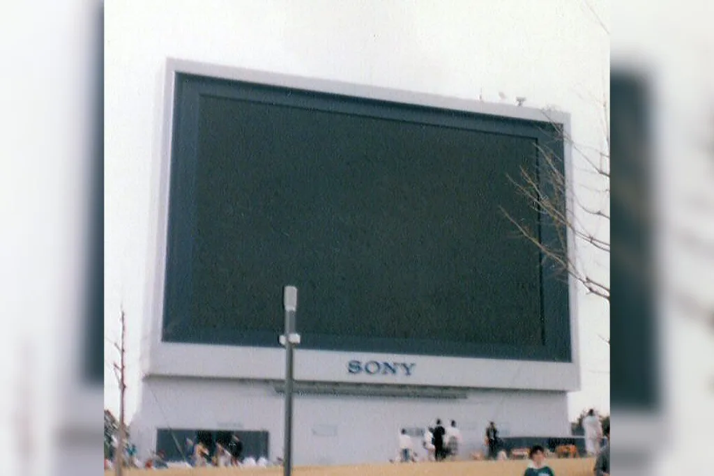 A large, outdoor, wall-mounted Sony-branded screen is shown with its display turned off, appearing as a dark rectangle…