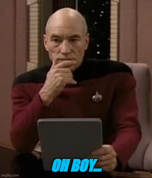 A man in a red Starfleet uniform from Star Trek: The Next Generation sits at a desk with a laptop, hand on chin in a…