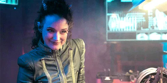 The image shows two women in a futuristic, neon-lit setting. The top row features a woman in a green jacket smiling…