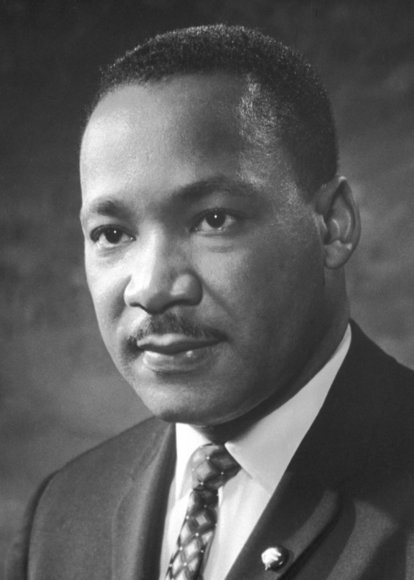 A black-and-white portrait of Martin Luther King Jr. wearing a suit and tie, looking directly at the camera. Overlaid text…