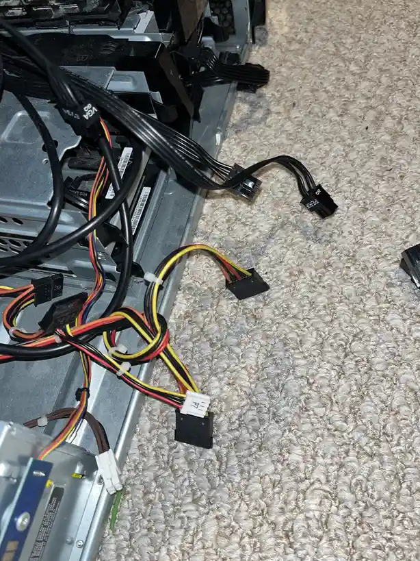 A close-up photo shows the inside of a computer case with various colorful SATA and power cables dangling and disconnected…