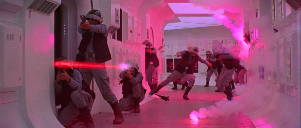 A scene from Star Wars: Episode V - The Empire Strikes Back shows Rebel soldiers in a corridor under pink lighting, firing…