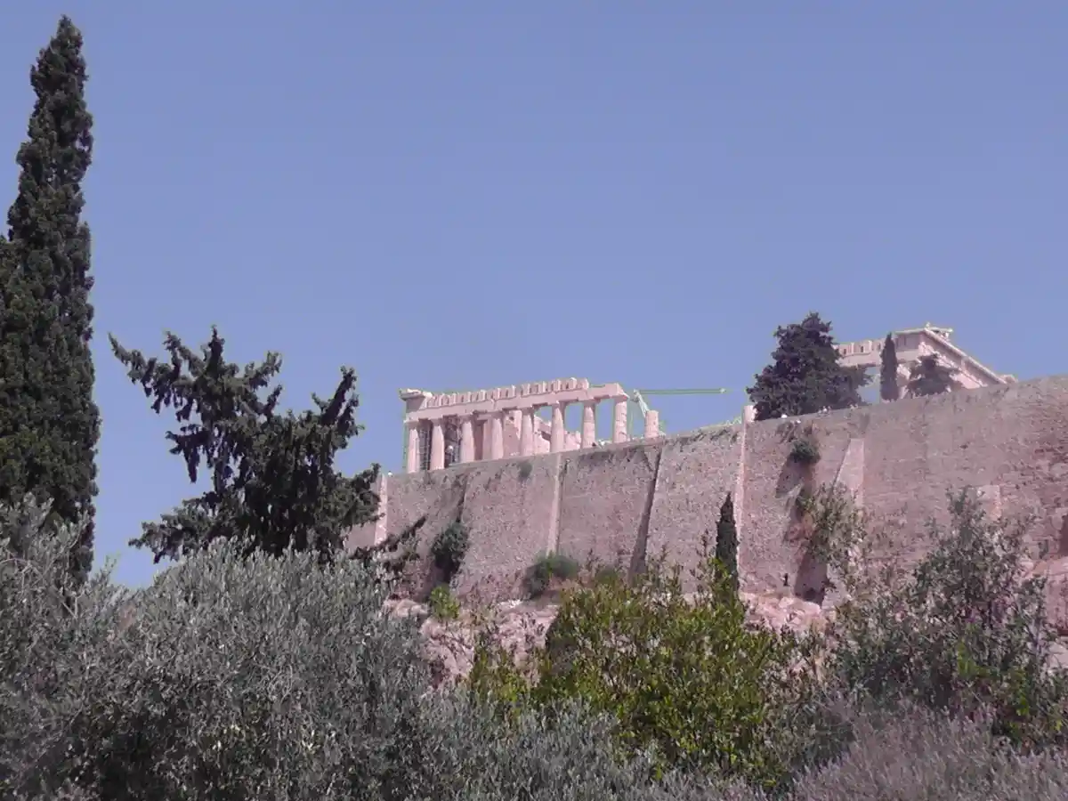 The image shows the ancient Parthenon temple on the Acropolis of Athens, but with an unnatural pink tint applied to the…