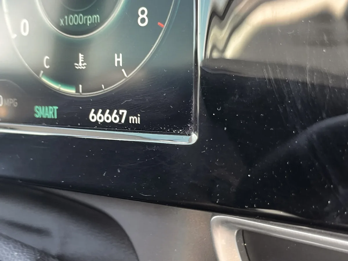 A close-up of a car's digital odometer showing 66667 miles, with the word 'SMART' illuminated in green nearby. The dashboard…