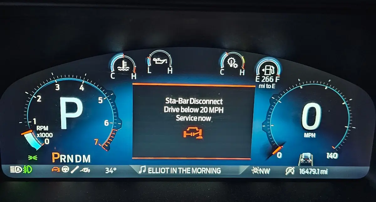 A car's digital dashboard displays a warning message reading 'Sta-Bar Disconnect, Drive below 20 MPH, Service now' while the…