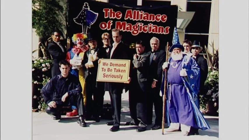 A group of men dressed as magicians, clowns, and wizards pose for a photo in front of a banner reading 'The Alliance of…