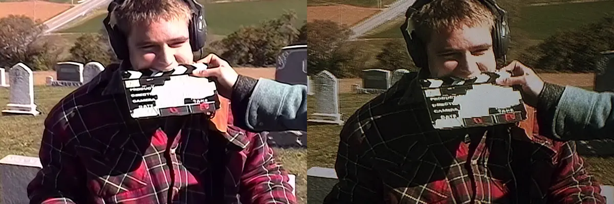 A man wearing headphones and a plaid jacket is in a cemetery, smiling as another person holds a clapperboard in front of his…