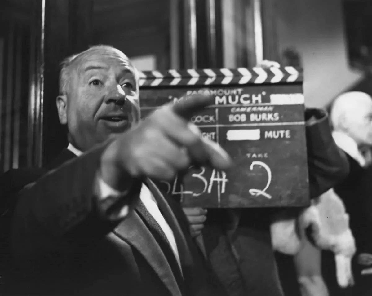 A black-and-white photo shows a man in a suit holding a clapperboard that reads 'PARAMOUNT' and 'MUCH' with 'CAMERAMAN BOB…