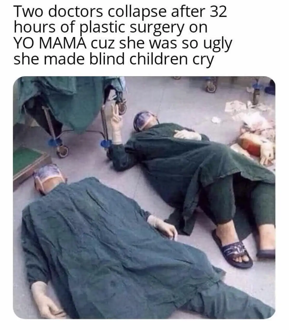 Two people in green surgical scrubs and caps are collapsed on a hospital floor, appearing exhausted. One is lying face down…