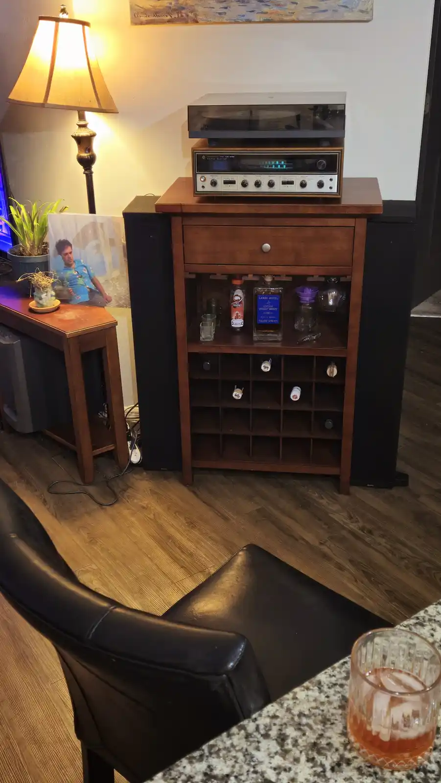 A cozy room features a wooden cabinet with a vintage stereo receiver and turntable on top, flanked by large black speakers…