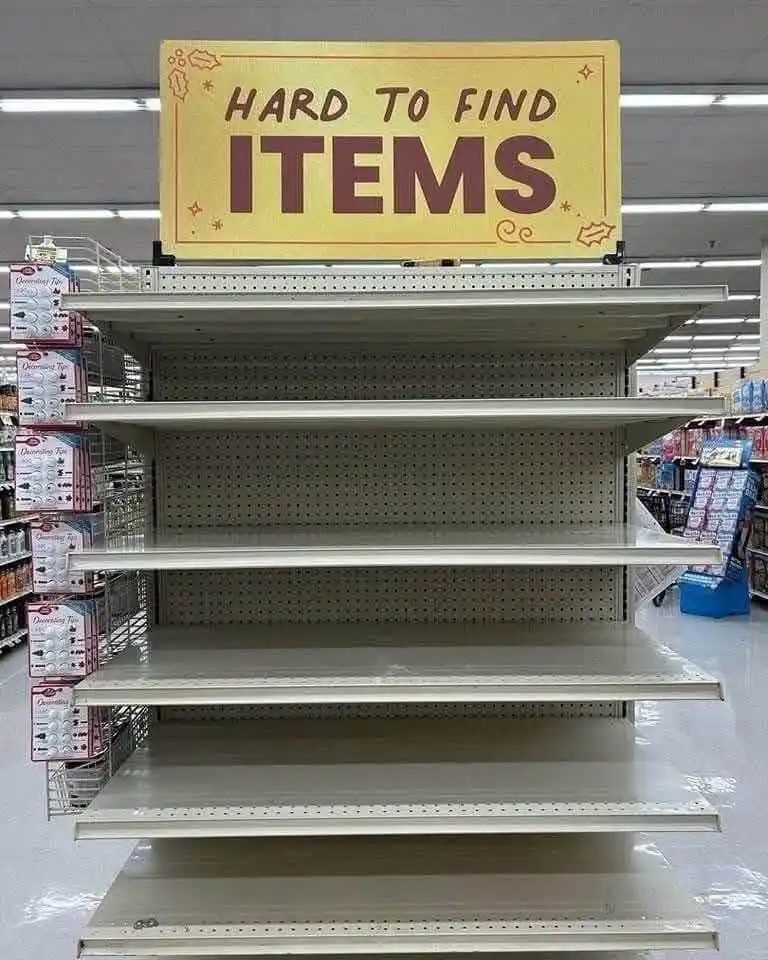 A large yellow sign reading 'HARD TO FIND ITEMS' is mounted above completely empty supermarket shelves, creating a stark…