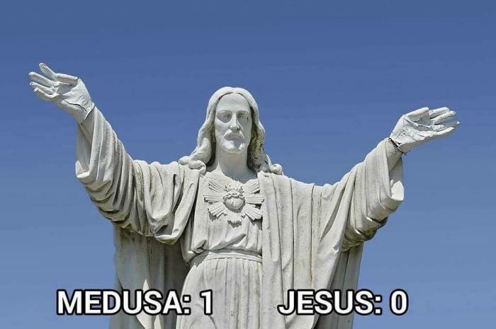 A large stone statue of Jesus Christ with arms outstretched against a clear blue sky. White bold text at the bottom reads…