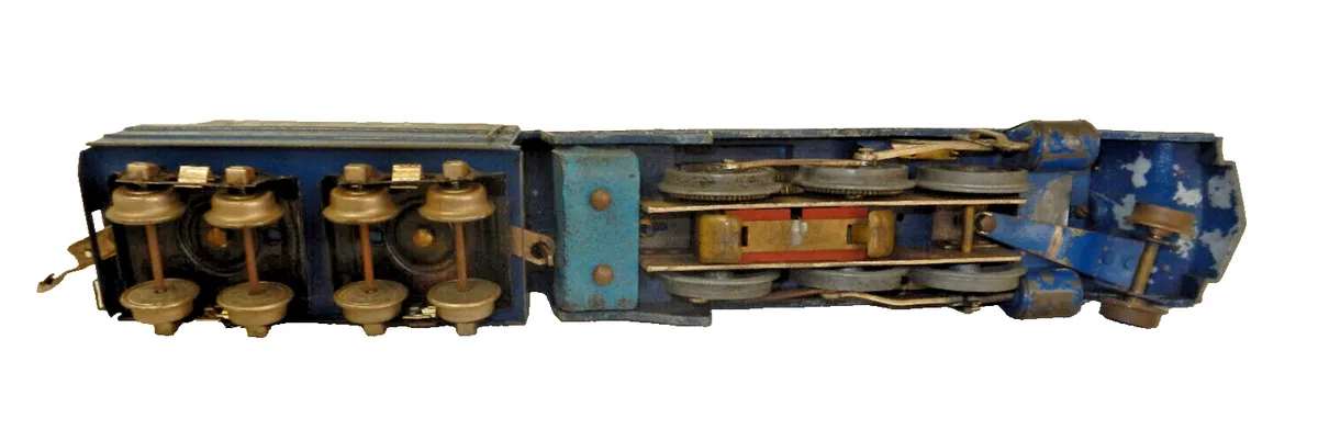 The image shows the open, internal mechanical components of a blue train car, revealing gears, wheels, and brass fixtures…