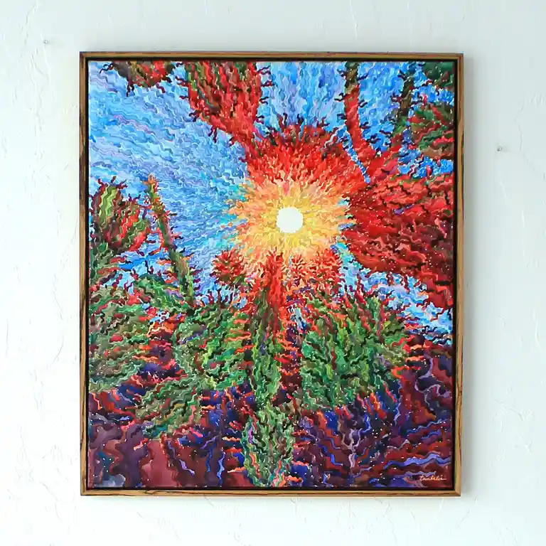 A framed abstract painting hangs on a white wall, depicting a vibrant, sunburst-like center radiating reds, oranges, and…