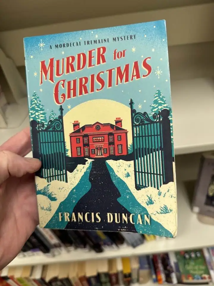 A hand holds up a book titled 'Murder for Christmas' by Francis Duncan, part of the Mordecai Tremaine Mystery series. The…