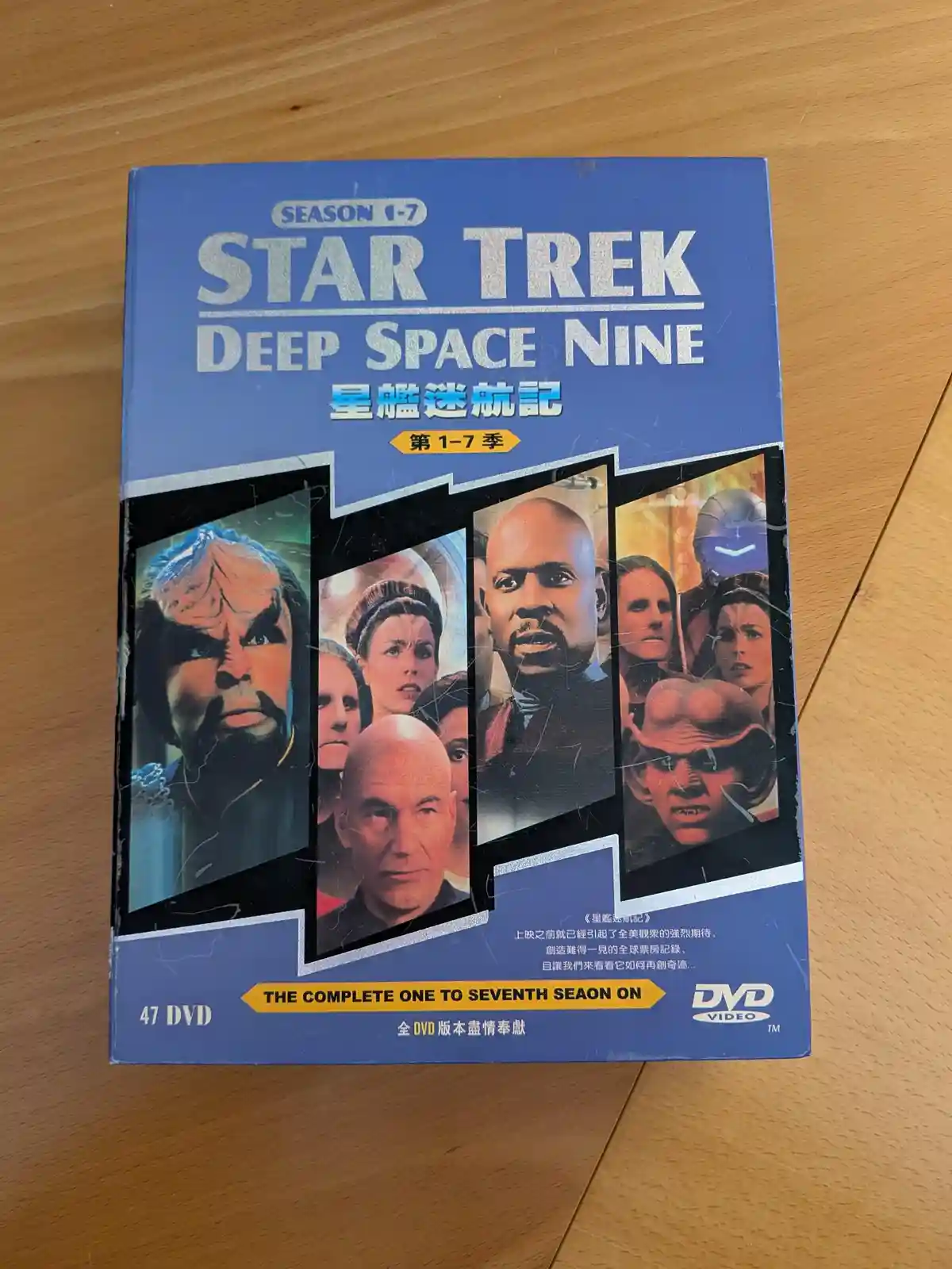 A blue DVD box set for 'Star Trek: Deep Space Nine' seasons 1-7, featuring character portraits and Chinese text, sits on a…