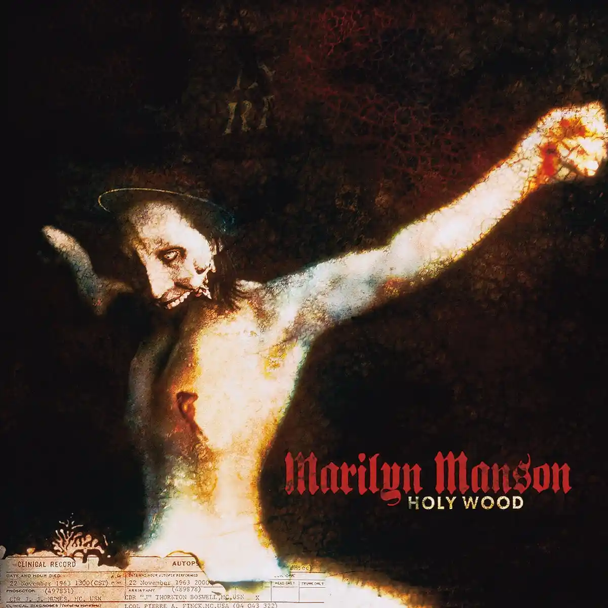 The image is the album cover for Marilyn Manson's 'Holy Wood,' featuring a distorted, pale figure resembling a crucified…