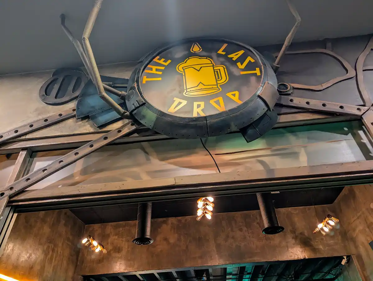 A circular, industrial-style sign with a beer mug logo and the text 'THE LAST DROP' in yellow letters on a dark background…