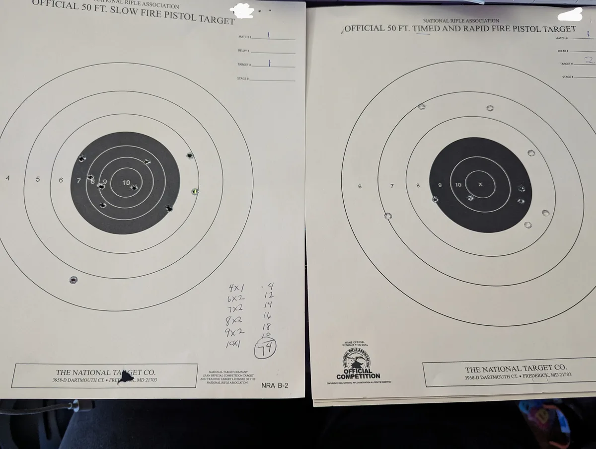 Two NRA pistol targets side-by-side; the left 'slow fire' target has a score of 74 with shots scattered across rings, while…