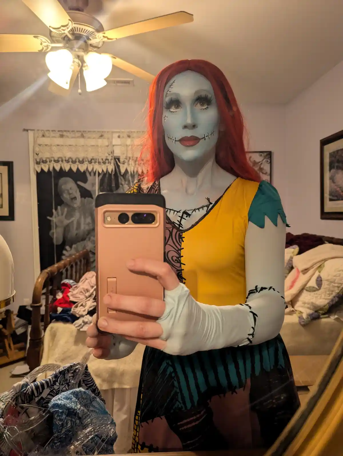 A person in a full Sally cosplay from The Nightmare Before Christmas, with blue face paint, red wig, and stitched costume…