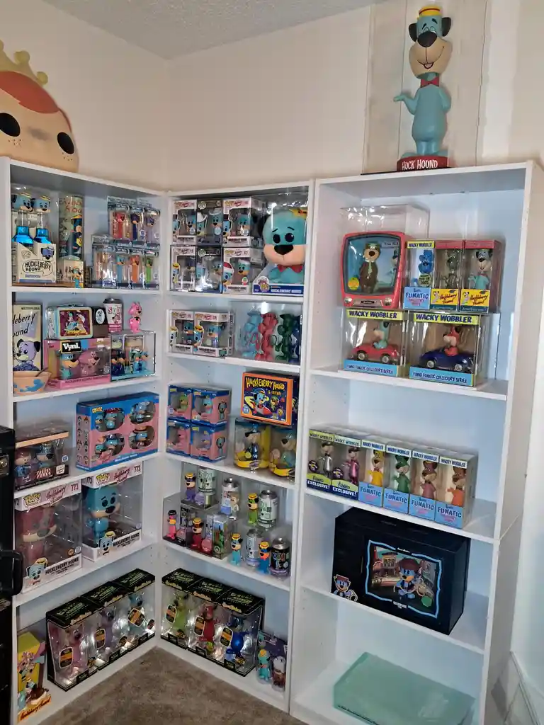 A corner of a room filled with white shelves displaying a massive collection of Huckleberry Hound merchandise, including…