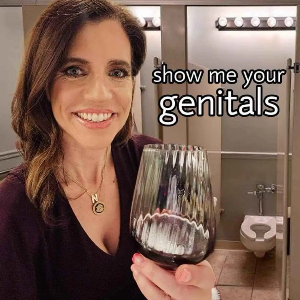A woman with brown hair and a dark top smiles while holding a wine glass in a bathroom, with the text 'show me your…